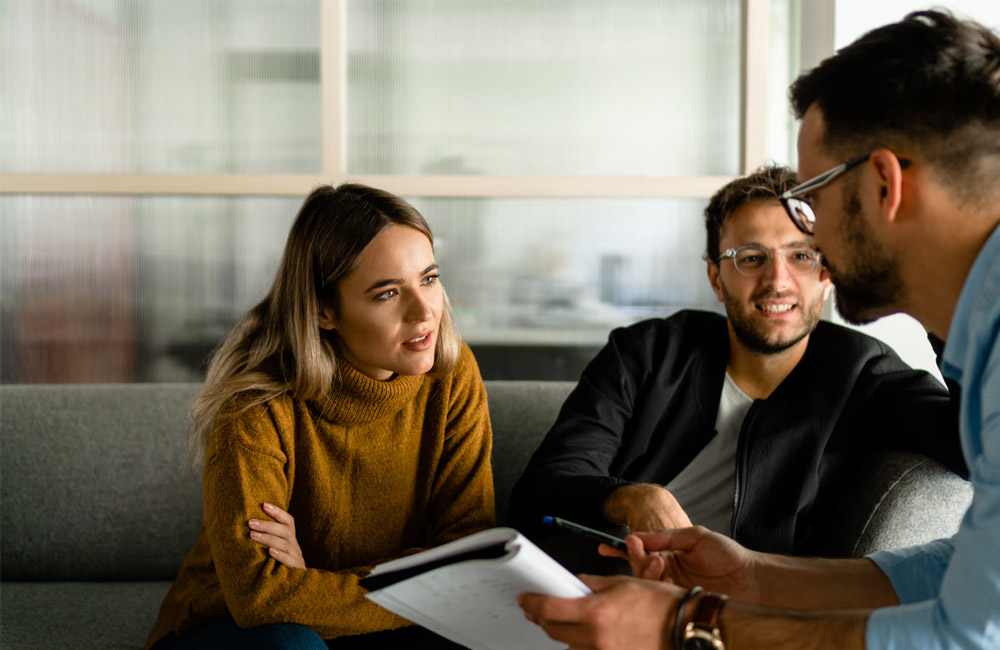 A man and woman sitting on a couch talking about finance with a sales rep