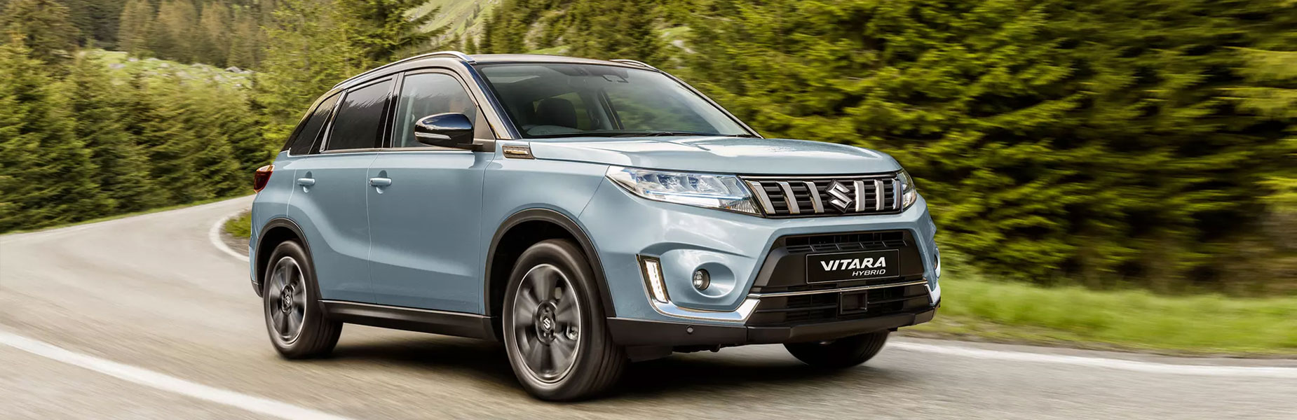 Ice blue Vitara Hybrid driving but a forest