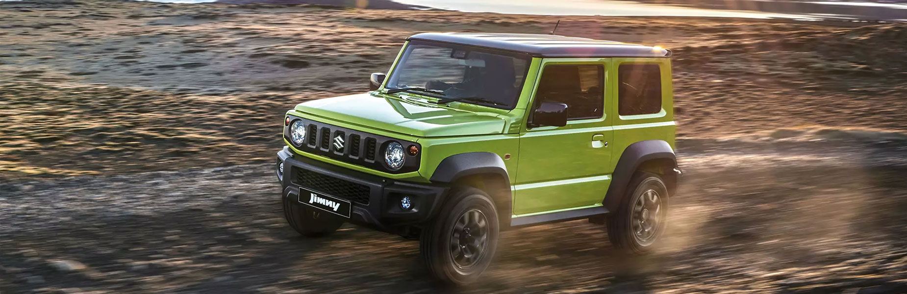 Green Jimny driving along a beach